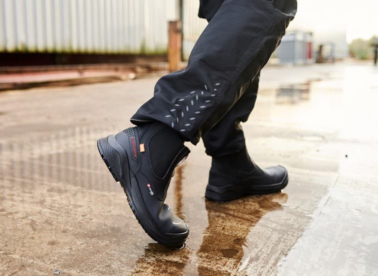 Sixton Forte werkschoenen onder een donkere werkbroek op een natte buitenomgeving